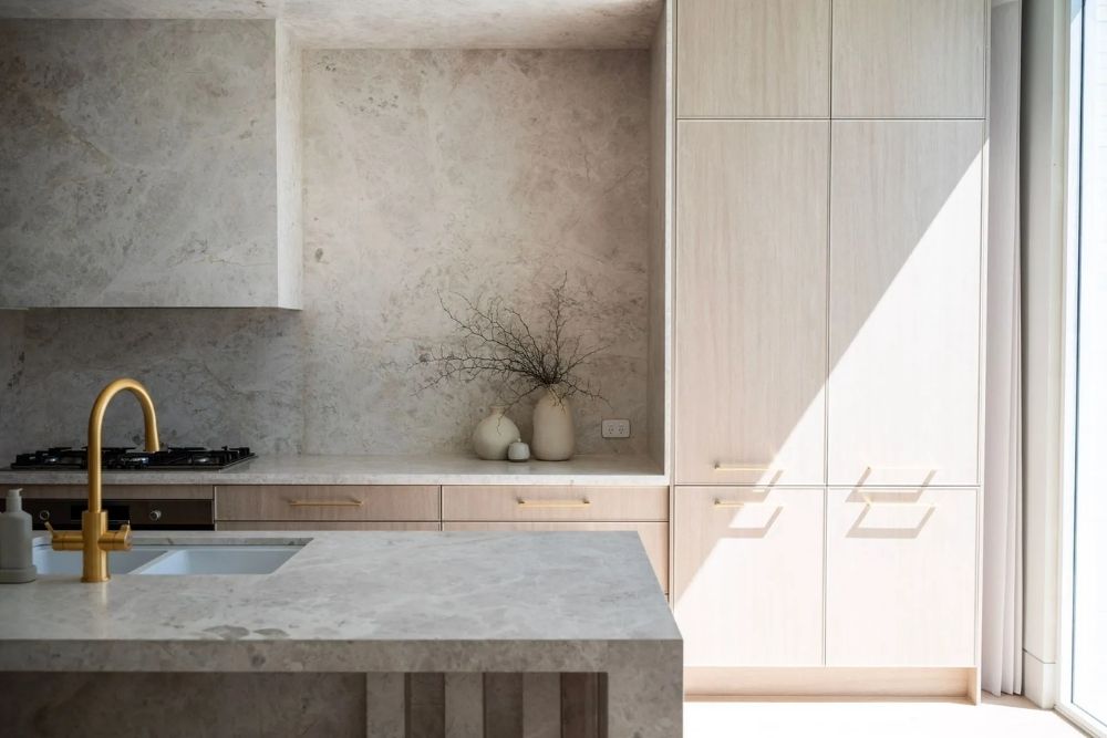 Modern, clean kitchen interior featuring marble stone benches and bright natural lighting-